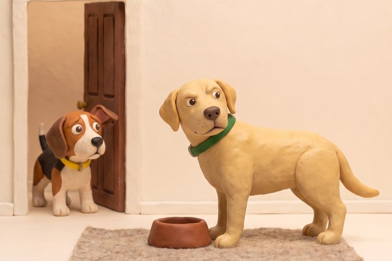 Ein Beagle-Welpe steht im T&uuml;rrahmen, der Labrador schaut vom Napf auf